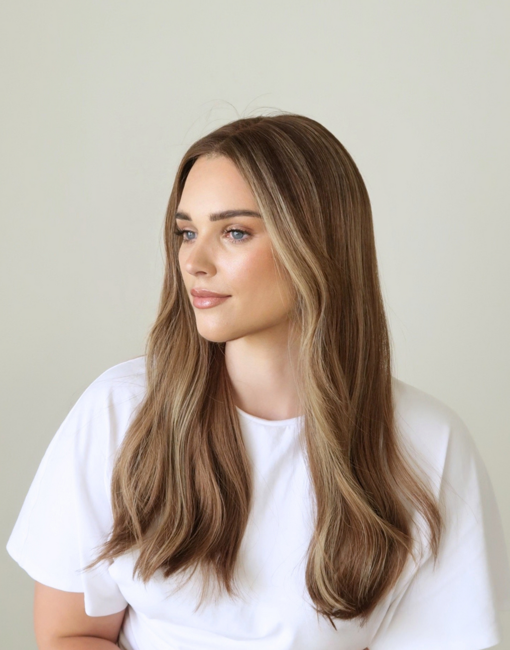 Side close-up of Amber 20-inch human hair wig, showing toasted almond brown color and softly blended highlights around the face.