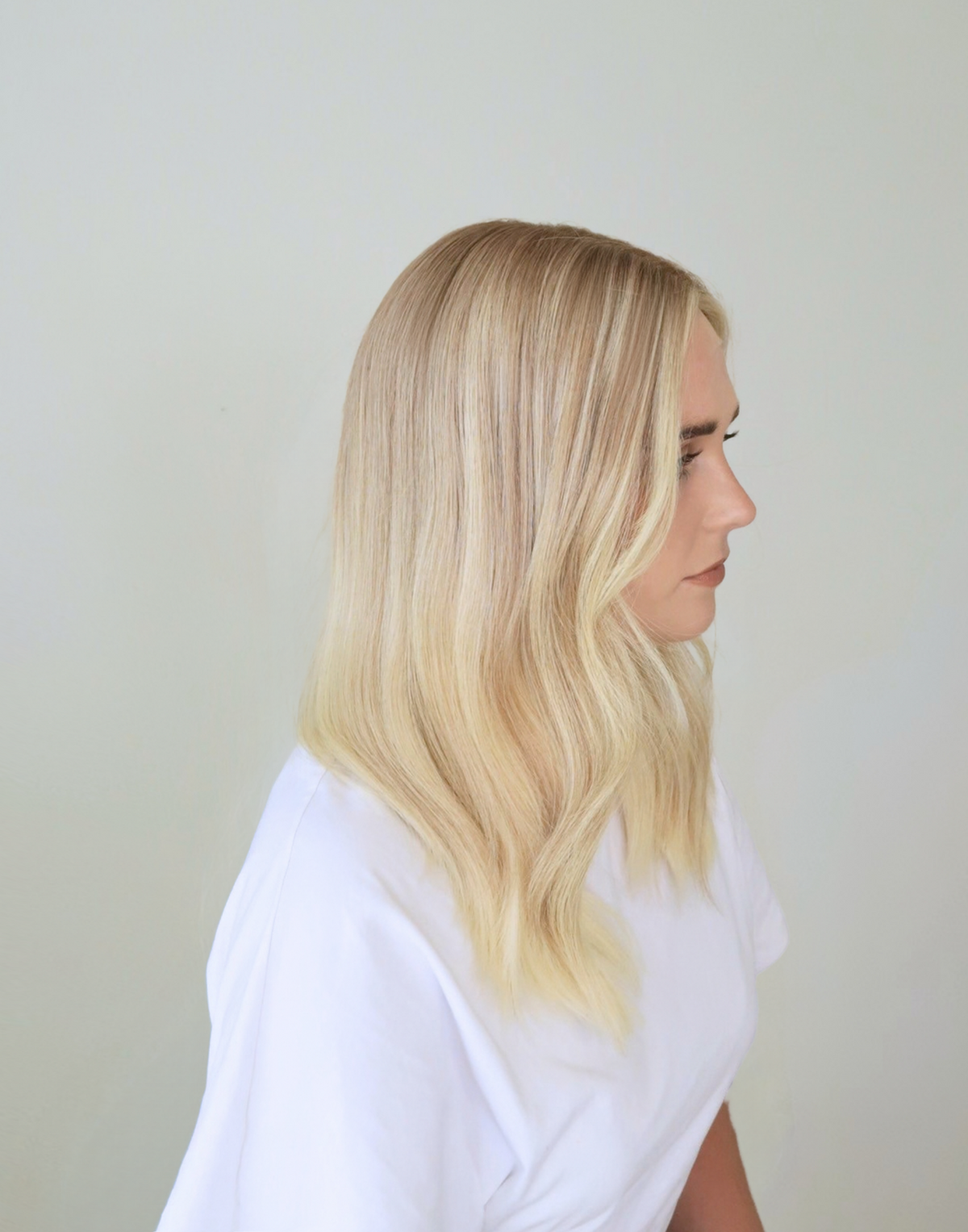 Side view of Chantilly vanilla blonde Remy human hair wig, featuring softly blended babylights and a subtle shadow root.