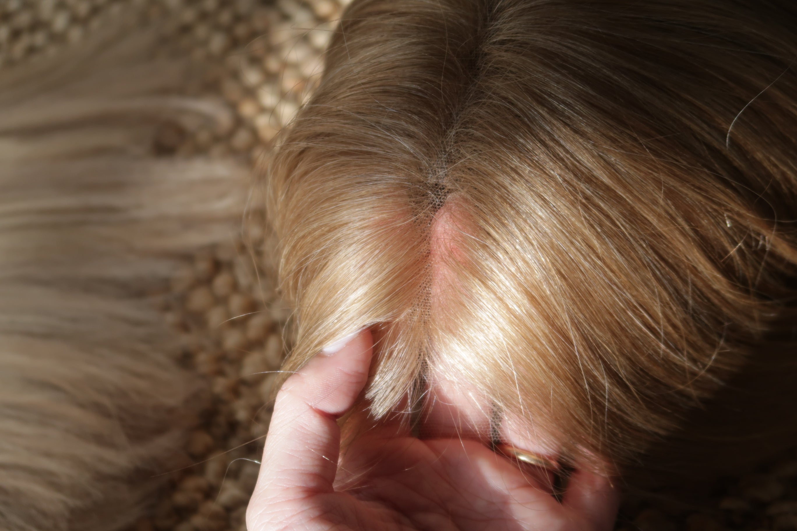 Close-up of a Madeline Aken lace top wig being inspected in natural light, showing hair quality and construction detail