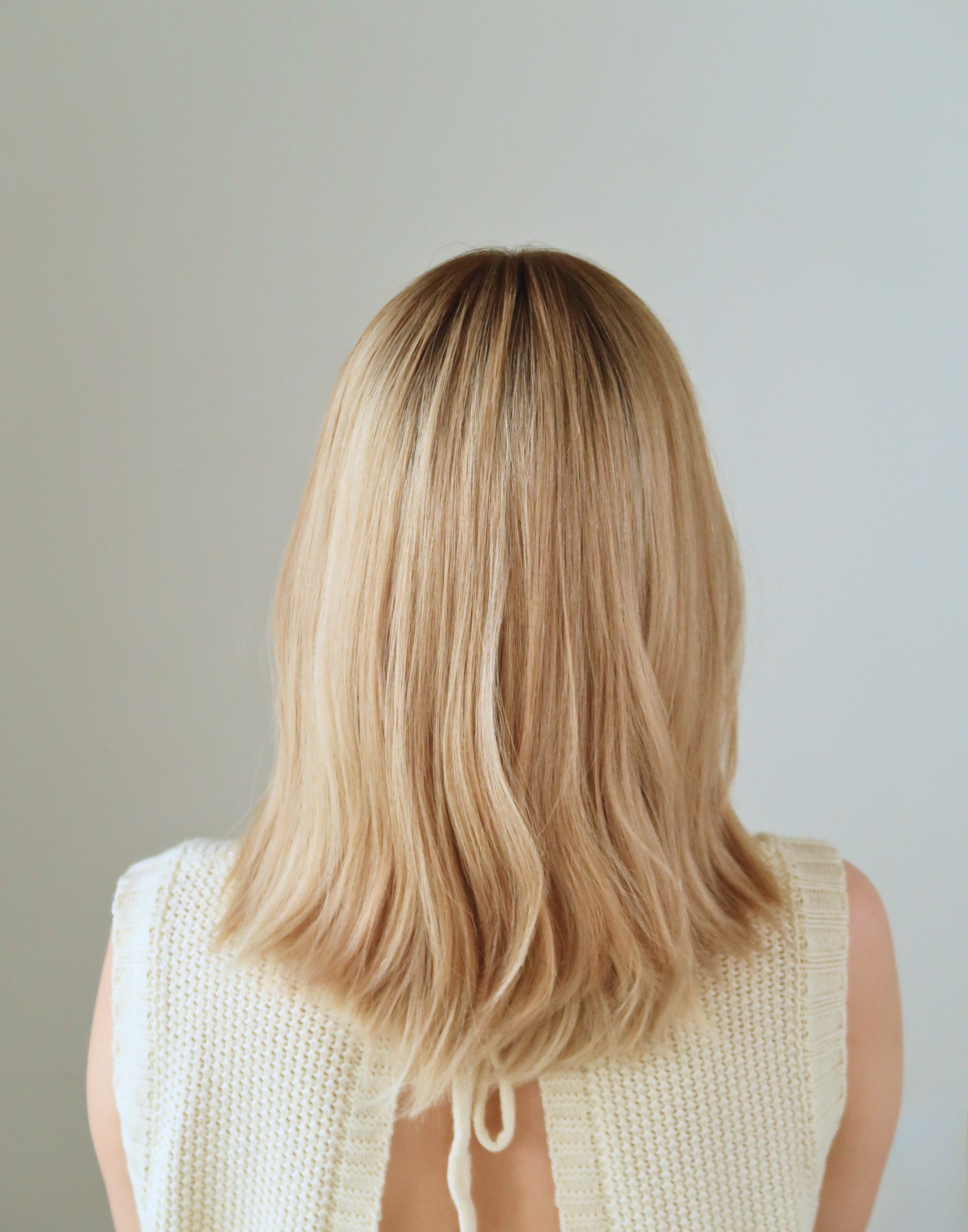 Model wearing the Mica beige blonde Remy human hair wig, showing its deep root, soft tonal dimension, and natural movement in daylight.